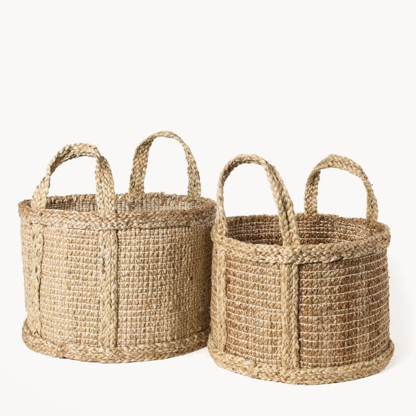 Two round woven braided baskets in a natural jute with large handles on a white background