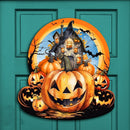 Halloween-themed door decoration with pumpkins and a haunted house on a teal door, surrounded by Christmas garland.