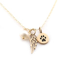 Gold necklace with angel wing, pearl  and paw print charm on a white background