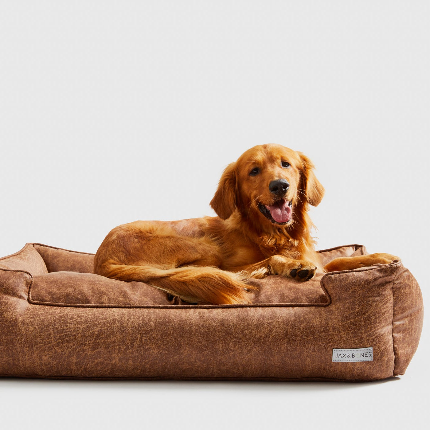 Dog lying on a Natural Vintage Lounge Pet Bed in Brown Faux Leather, with a Removable Cover and Wipes Clean