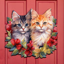 Decorative Christmas front door sign with two cats and floral designs, surrounded by Christmas garlands and decorations.