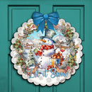 Decorative Christmas wreath with snowman and 'Let it Snow' text on a teal door, surrounded by garland and lights.