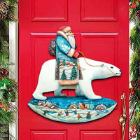 Decorative door hanger with Santa Claus and polar bear on a red door, surrounded by Christmas decorations.