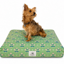 Small brown terrier dog sitting on a green rectangle Dog bed with a Minimalist pink floral pattern reminiscent of Dutch folk art