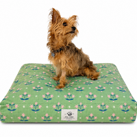 Small brown terrier dog sitting on a green rectangle Dog bed with a Minimalist pink floral pattern reminiscent of Dutch folk art