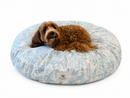 Dog lying on a blue and white patterned donut bed with a visible brand logo.