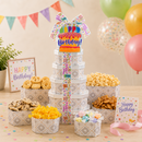 Birthday-themed snack set with cookies, popcorn, and a colorful 'Happy Birthday' sign on a wooden table.