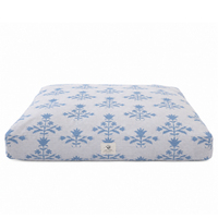 A rectangular dog bed with a light gray heathered fabric and a repeating blue botanical damask pattern, featuring a small white brand label on the front.