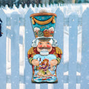 Traditional Nutcracker door hanger art on a white picket fence with a snowy background