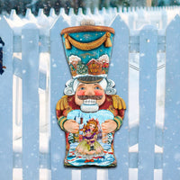 Traditional Nutcracker door hanger art on a white picket fence with a snowy background