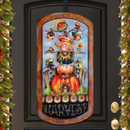 Decorative door hanging with scarecrow, pumpkins, and festive text on a black door.