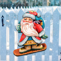 Decorative Santa Claus figure on a snowboard with a white picket fence in the background.
