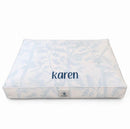 Personalized dog bed in light gray and white with dog name.