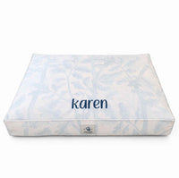 Personalized dog bed in light gray and white with dog name.
