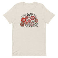 light beige/off-white unisex t-shirt with encouraging saying "it's okay to be different" in red, pink floral design