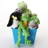 A collection of plush stuffed animals arranged inside a bright blue basket on a clean white background. The assortment includes a green frog with yellow spots and an orange belly, a black-and-white penguin with a white flower, a gray shark, a green dinosaur, and a gray-and-black spotted plush.